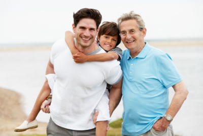 Photograph of a Healthy family-- three generations of males posing with the beach in the background