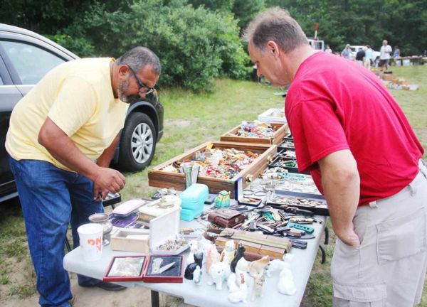 Photo of two men bent over trinkets at a stand at the sandwich flea market